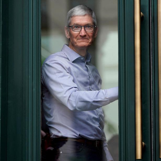 FILE PHOTO: pple Chief Executive Officer Tim Cook watches customers awaiting the grand opening of the new Apple Carnegie Library store in Washington