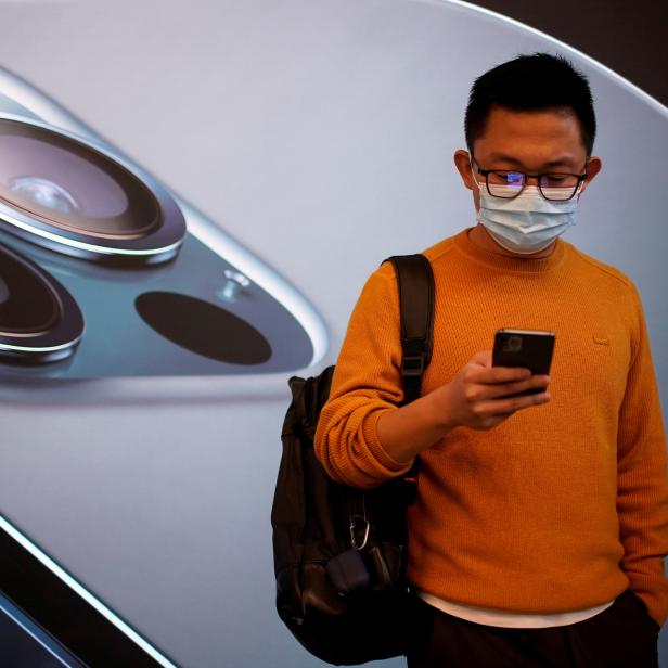 FILE PHOTO: A man wears a face mask while waiting at an Apple Store in Shanghai