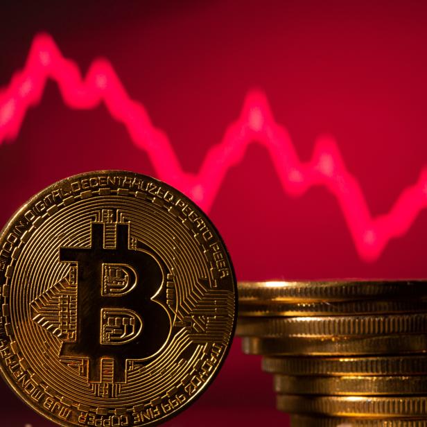 A representations of virtual currency Bitcoin is seen in front of a stock graph in this illustration