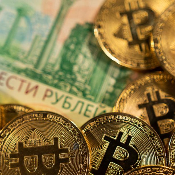 Illustration shows Russian rouble banknotes and representations of the cryptocurrency Bitcoin