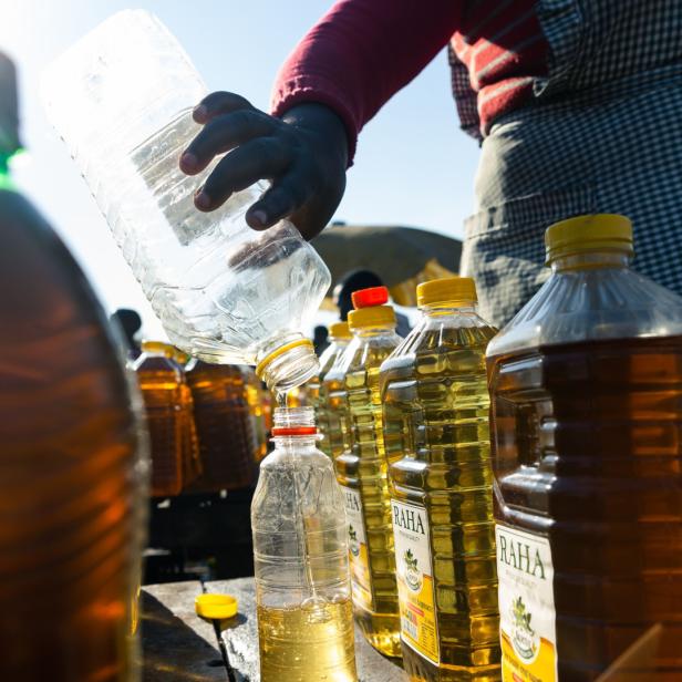 Eine Frau füllt Speiseöl von einer Flasche in eine andere um