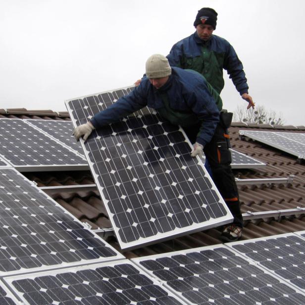 Zwei Männer installieren Solarmodule auf einem Dach