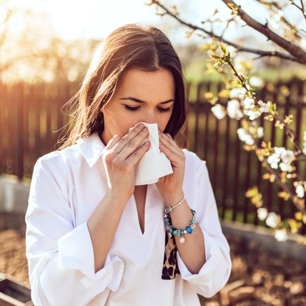 Woman sneezing in the blossoming garden