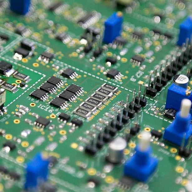 Eine grüne Platine mit elektronischen Bauteilen und Beschriftungen wie IC16 und B2RO.