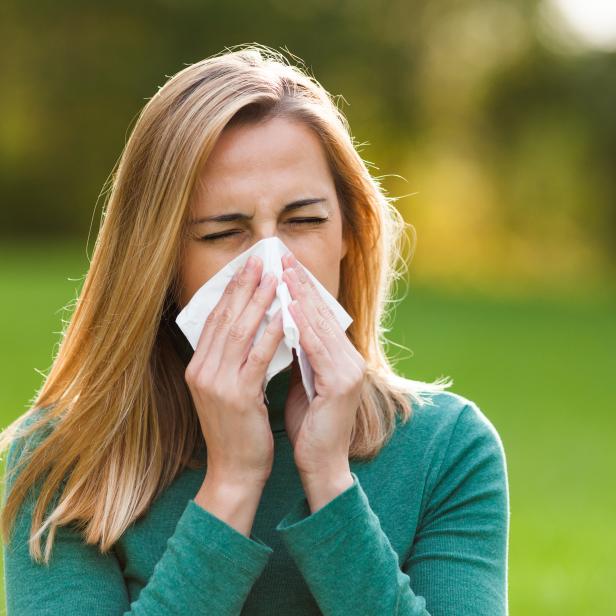 Woman with allergy symptom blowing nose