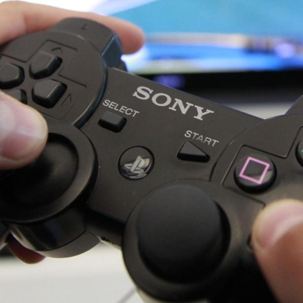 Ein schwarzer Sony PlayStation 3 Controller wird von Händen gehalten.