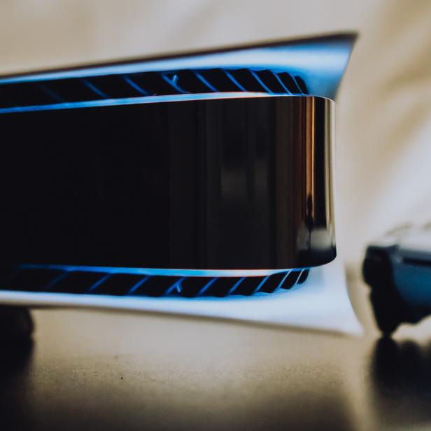 Eine Playstation 5 Konsole und ein Controller auf einem Tisch.