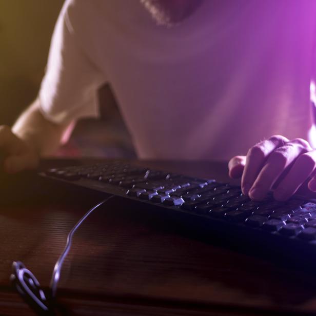 close up gamer hands on the keyboard playing video games in the night