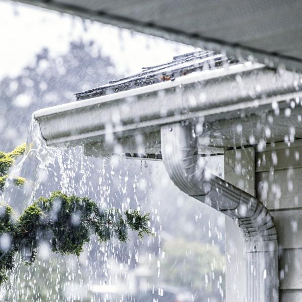 Regenwasser fließt von einem Dach in eine Dachrinne.