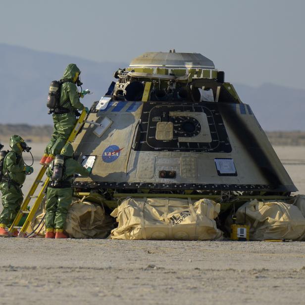 Personal in Schutzanzügen inspiziert die gelandete Boeing-Kapsel des Orbital Flight Test-2 der NASA.
