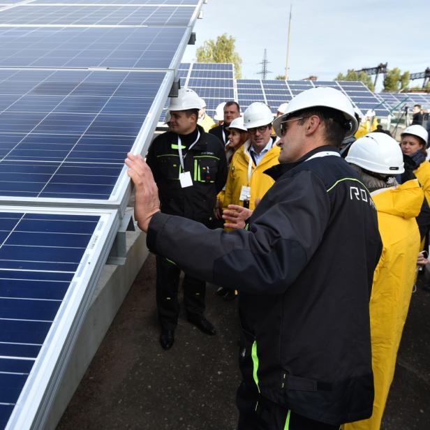 Menschen neben Photovoltaik-Modulen bei der Eröffnung eines Solarkraftwerks