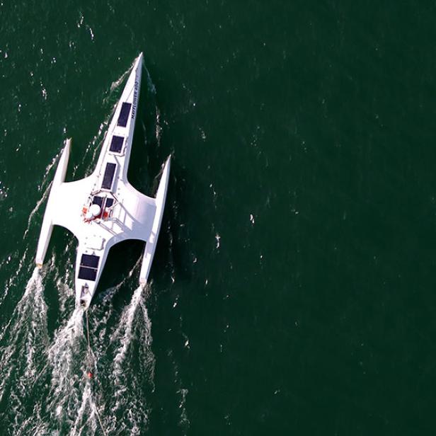Ein weißer Trimaran, möglicherweise die „Mayflower 400“, fährt auf dem Wasser.