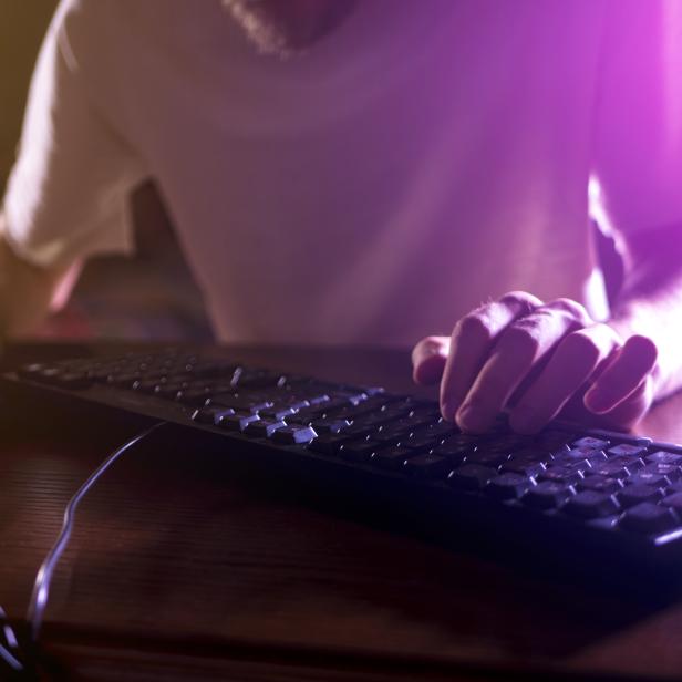 close up gamer hands on the keyboard playing video games in the night