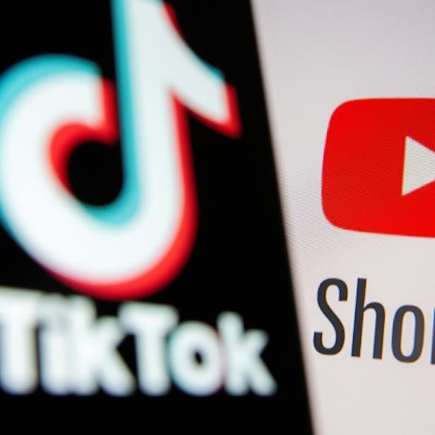 Tik Tok logo is seen on a smartphone in front of displayed Youtube Shorts logo in this illustration taken