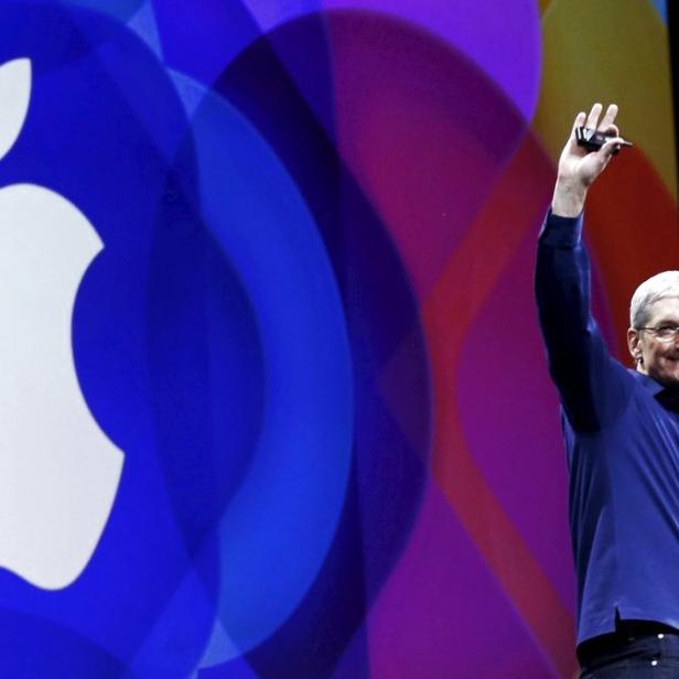 Tim Cook steht auf einer Bühne vor einem großen Apple-Logo und winkt.