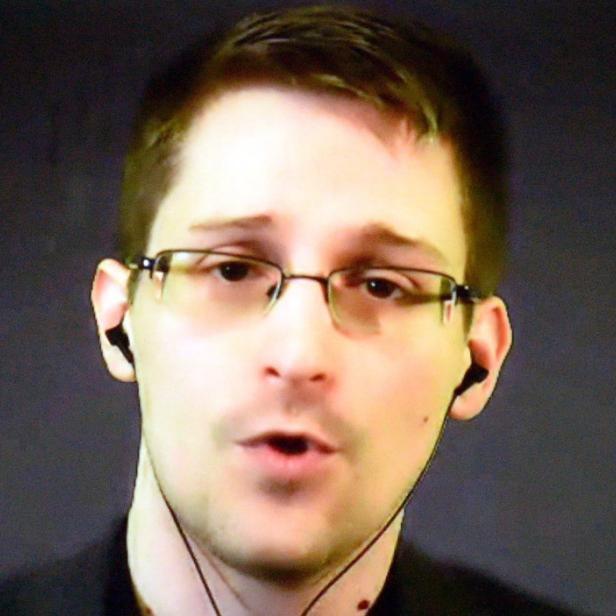 Edward Snowden spricht vor einem dunklen Hintergrund.