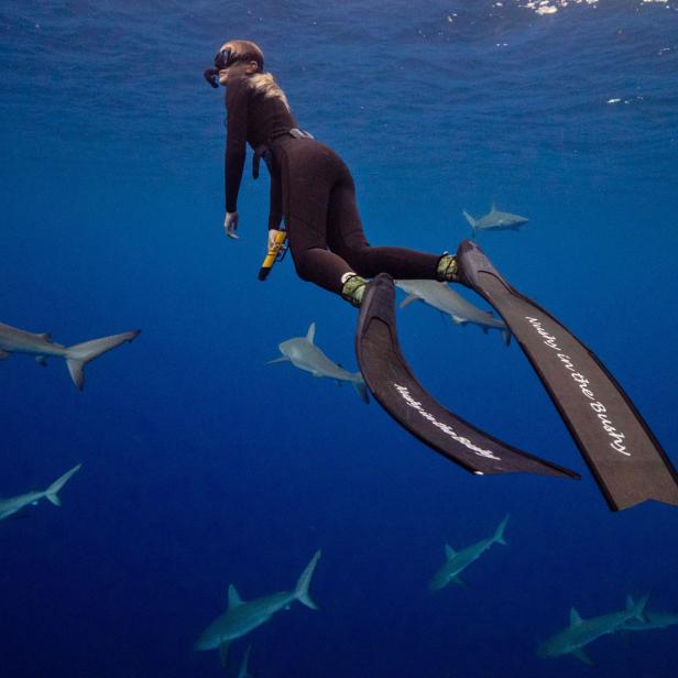 Frau mit Flossen unter Wasser mit Haien