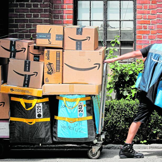 An Amazon delivery worker pulls a delivery cart full of packages during its annual Prime Day promotion in New York