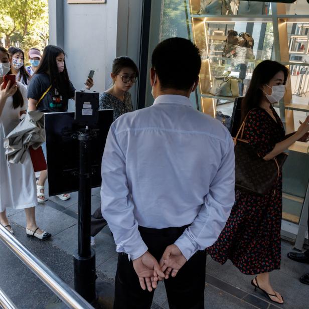 Security guards check the health code app of people entering a business area before office hours, following a coronavirus disease (COVID-19) outbreak, in Beijing