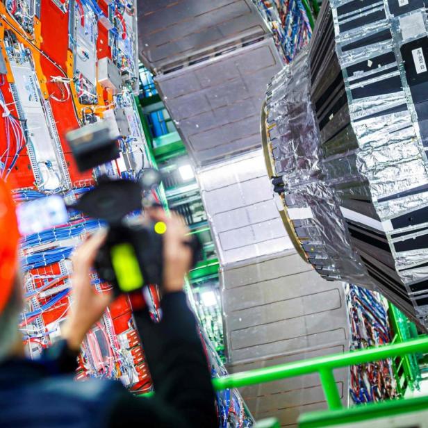 Ein Arbeiter mit Schutzhelm fotografiert den Large Hadron Collider.