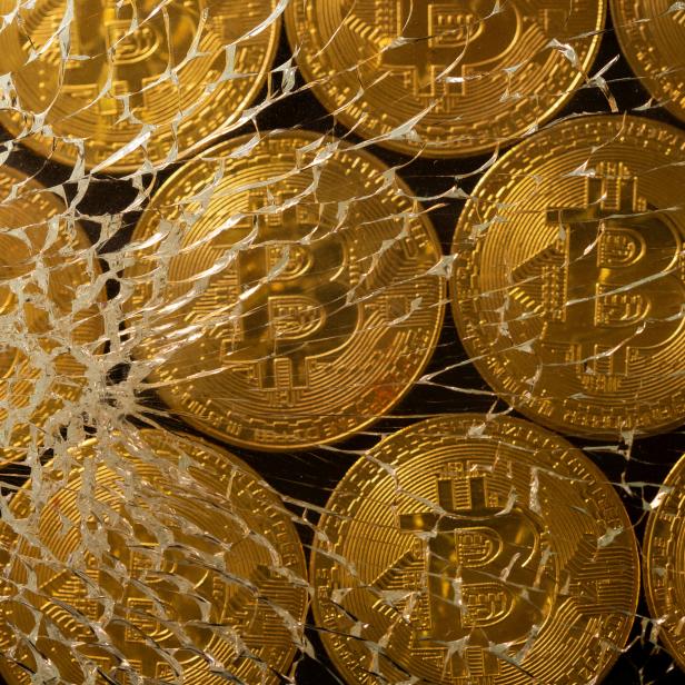 FILE PHOTO: Representations of virtual currency bitcoin are seen through broken glass in this illustration taken