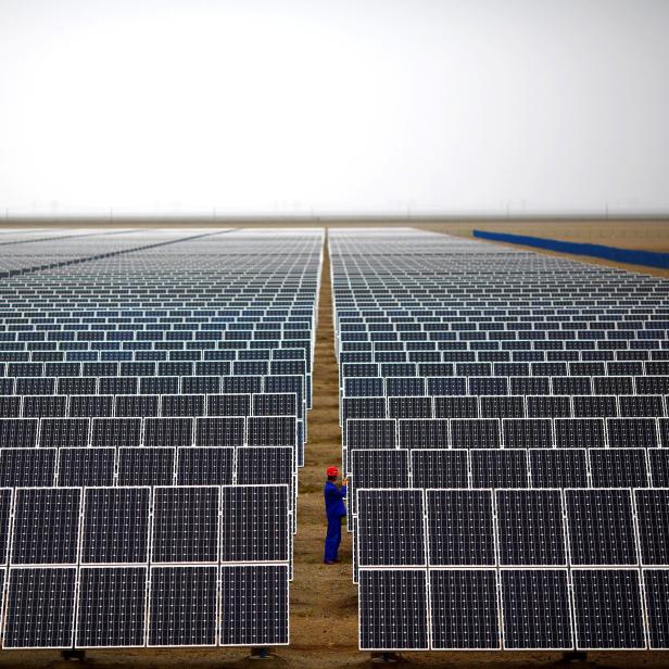 FILE PHOTO: A worker inspects solar panels at a solar farm in Dunhuang