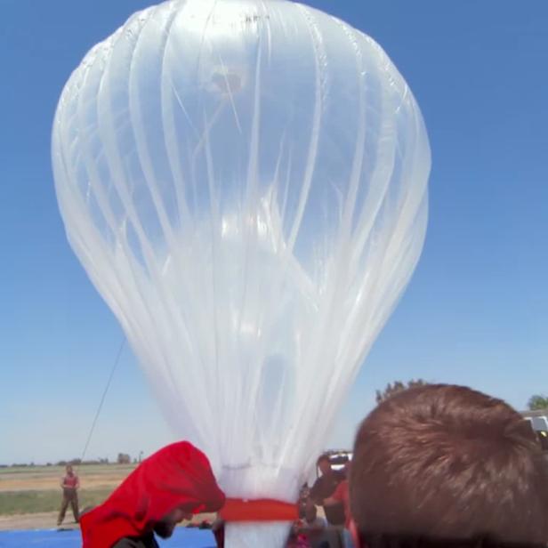 Ein großer, durchsichtiger Wetterballon wird für den Aufstieg vorbereitet.