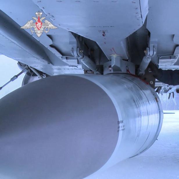 Ein russischer Soldat inspiziert eine Rakete unter einem Militärflugzeug.