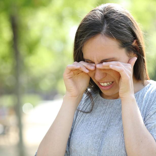 Disgusted woman rubbing her eyes in a park