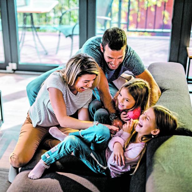 Above view of playful parents tickling their daughters at home.