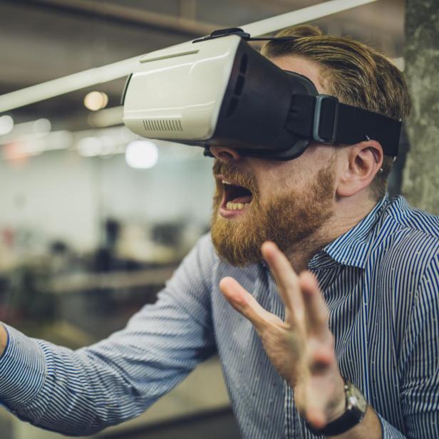 Young entrepreneur having fun on a break while using virtual reality simulator.