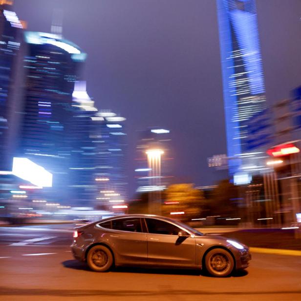 FILE PHOTO: A Tesla electric car drives past a crossing in Shanghai