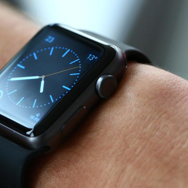 Eine Apple Watch mit schwarzem Armband wird am Handgelenk getragen.