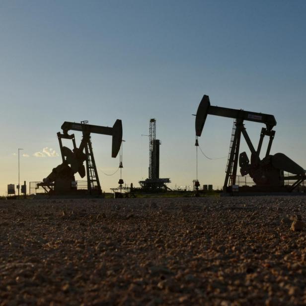 FILE PHOTO: Pump jacks operate in front of a drilling rig in an oil field in Midland