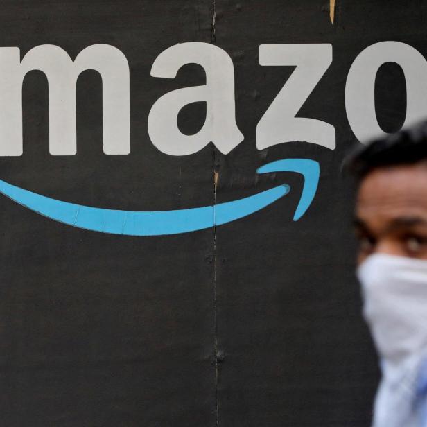 FILE PHOTO: A man walks past an Amazon logo outside the company's collection point in Mumbai