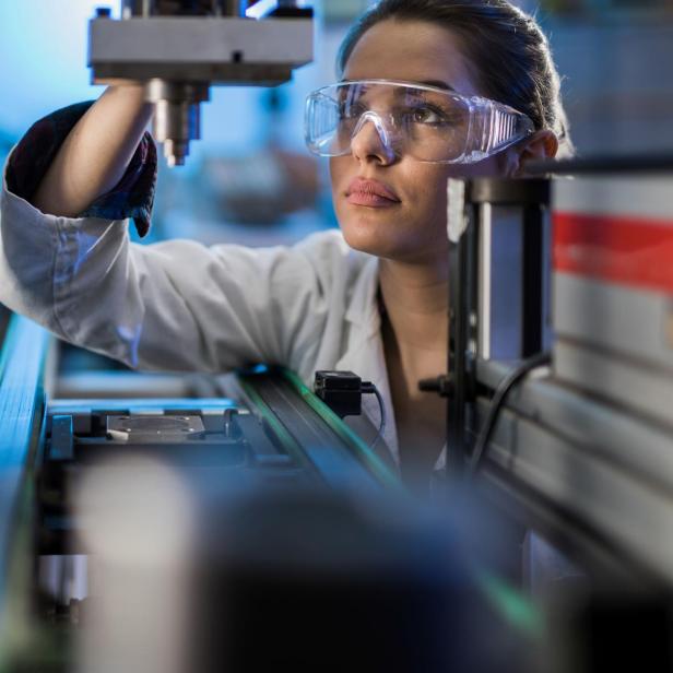 Female engineer examining machine part on a production line.