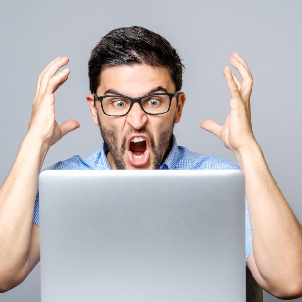 Portrait of amazed man with laptop computer over gray background