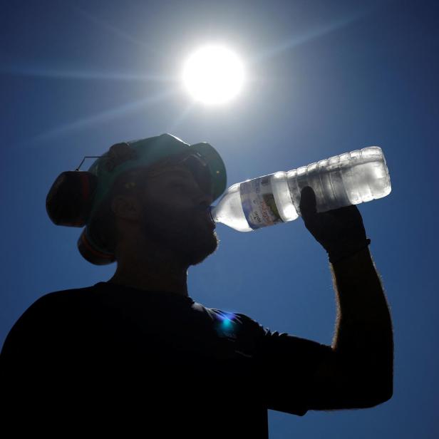 A worker drinks water on a road site in Aigrefeuille-sur-Maine