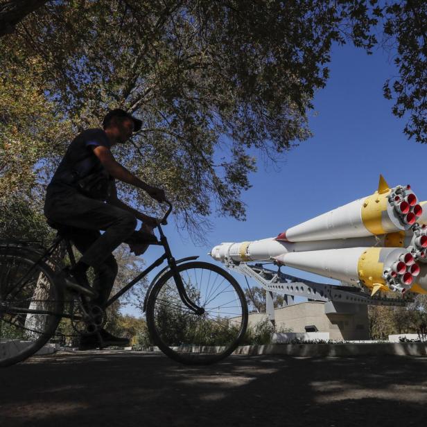 Mann auf Fahrrad vor Denkmal in Baikonur