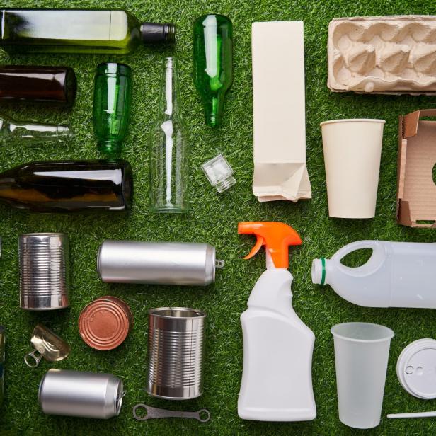 A selection of garbage for recycling. Segregated glass, metal, plastic and paper on green grass background.