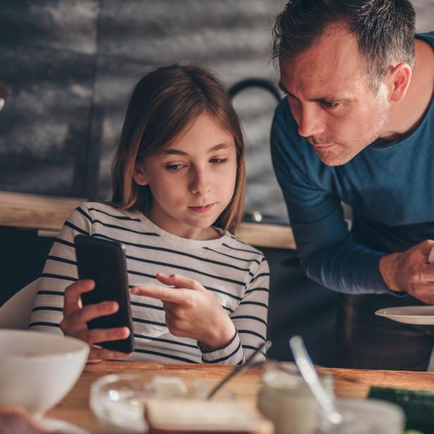 Daughter showing text message to a father