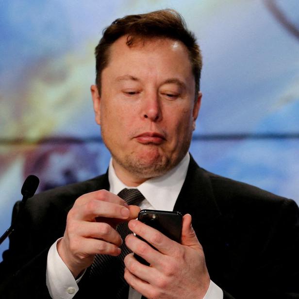 FILE PHOTO: Elon Musk looks at his mobile phone