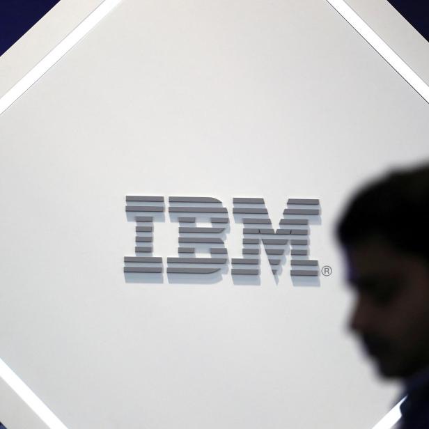 FILE PHOTO: A man stands near an IBM logo at the Mobile World Congress in Barcelona