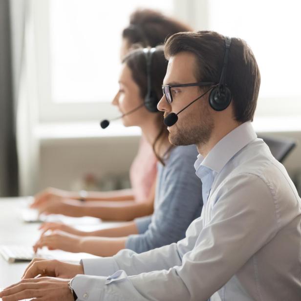 Male call center agent in wireless headset consulting online client