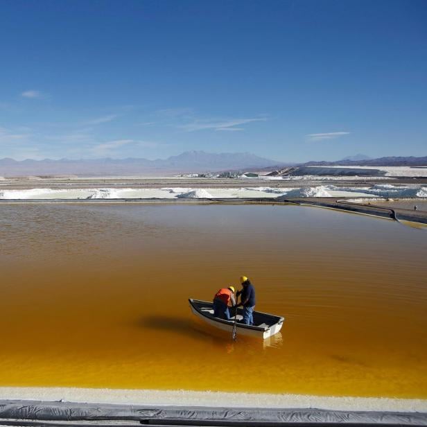 FILE PHOTO: Workers use a boat to take samples from a brine pool at the Rockwood Lithium plant on the Atacama salt flat