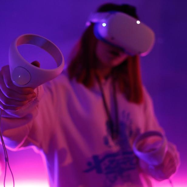 Eine Person mit einem VR-Headset hält einen Controller in der Hand.