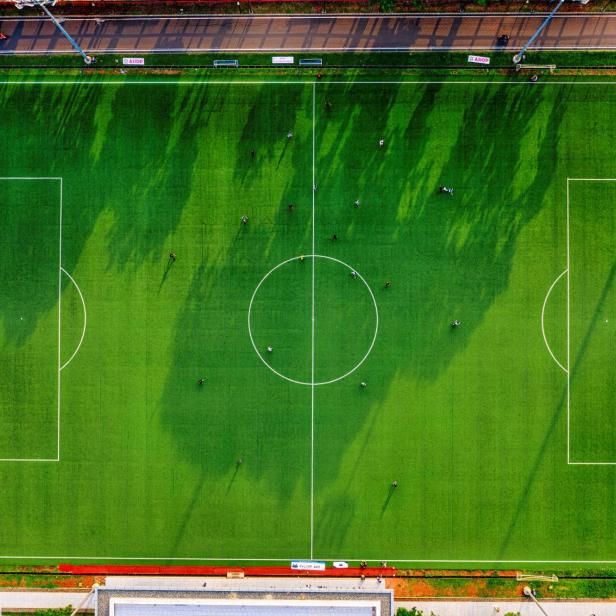 Ein Fußballfeld mit spielenden Personen, aufgenommen aus der Vogelperspektive.