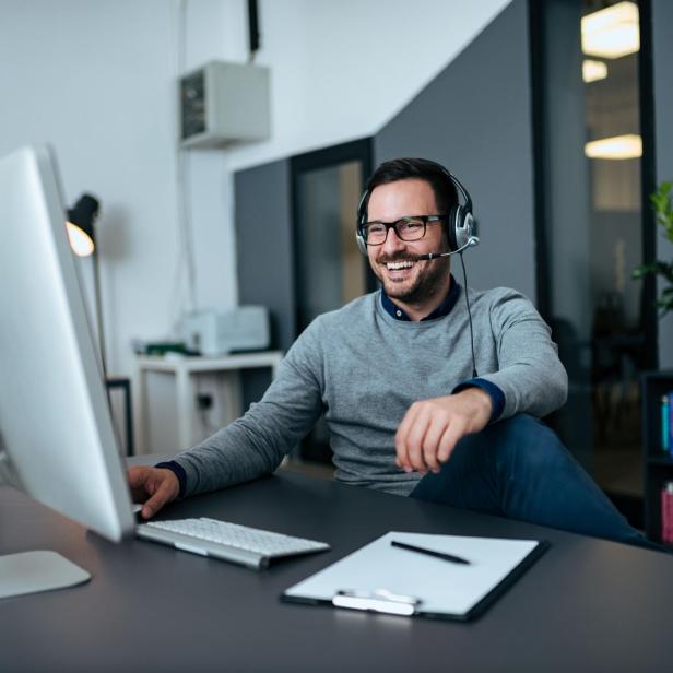 Handsome casual businessman talking online via headset.