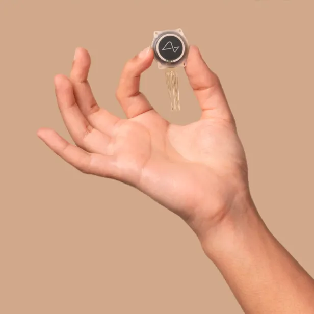 Der Gehirnchip von Neuralink wird von einer Hand gehalten. 