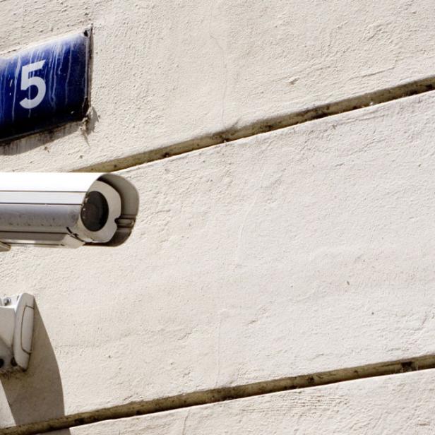 Eine Überwachungskamera ist an einer weißen Wand neben einem Schild mit der Nummer 5 montiert.